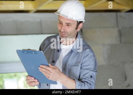 man builder se tient avec un presse-papiers à l'intérieur Banque D'Images