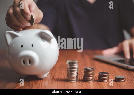 homme d'affaires tenant des pièces de monnaie mettant dans la banque de piggy. concept d'économie d'argent pour la comptabilité financière. Banque D'Images