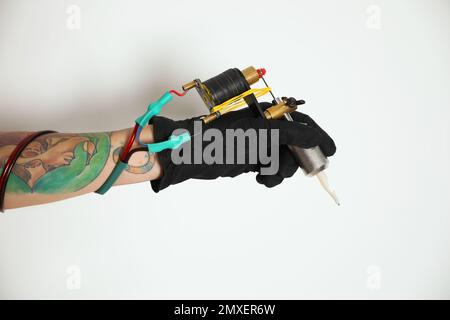 Tatouage artiste avec machine professionnelle sur fond blanc, gros plan Banque D'Images