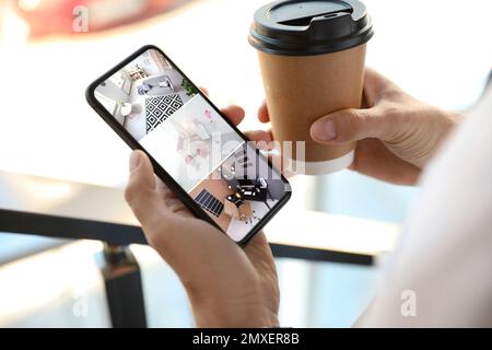 Homme surveillant des caméras CCTV modernes sur un smartphone à l'intérieur, en gros plan. Système de sécurité domestique Banque D'Images