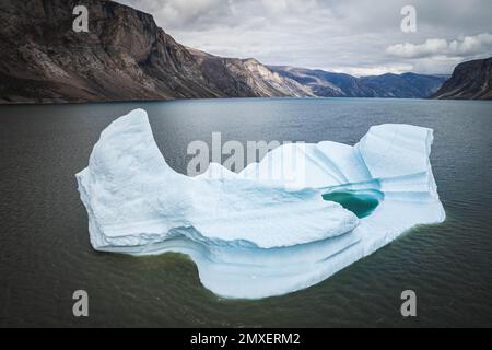 Grand iceberg bleu qui se reflète dans les flotteurs d'eau dans la mer par Broughton Island, Nunavut, Canada. Banque D'Images