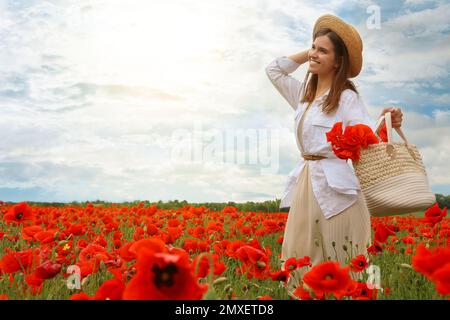 Femme tenant un sac à main avec des fleurs de pavot dans un beau champ Banque D'Images