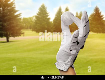 Joueur tenant une balle de golf dans le parc le jour ensoleillé, gros plan. Espace de conception Banque D'Images