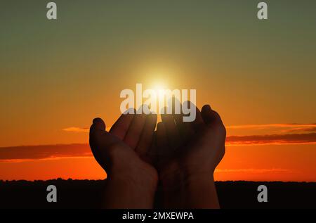 Femme musulmane priant à l'extérieur au coucher du soleil, en gros plan Banque D'Images