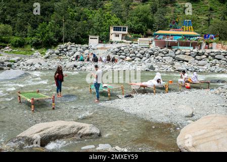 Les Pakistanais apprécient frais sur charpai (lits en bois) sur les rives de la rivière Swat en été, Swat Valley, Pakistan Banque D'Images