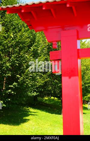 Détail de bord de style japonais, porte d'entrée en bois rouge à l'intérieur des arbres verts dans la nature en une journée ensoleillée Banque D'Images