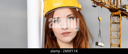 Bannière ou affiche supérieure horizontale avec une jeune femme roulante du chantier de construction portant un gilet de sécurité et un casque de sécurité - arrière-plan du chantier de construction avec Banque D'Images