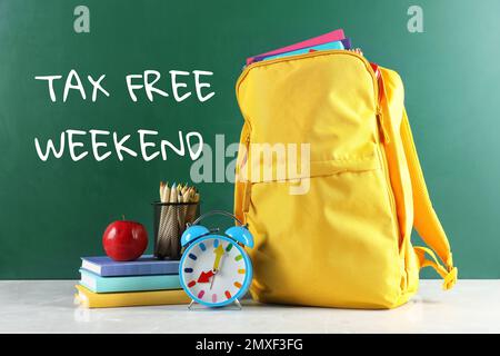 Sac à dos avec papeterie scolaire et texte HORS TAXE WEEK-END écrit sur tableau noir dans la salle de classe Banque D'Images