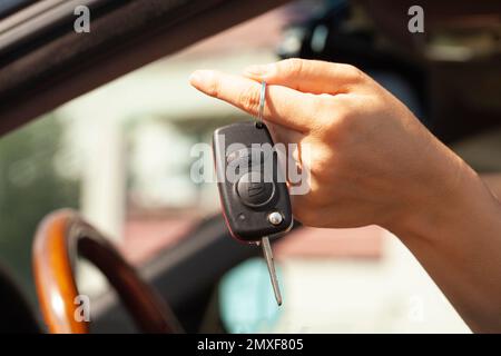 Clé de voiture dans la main d'une femme avec la voiture. Banque D'Images