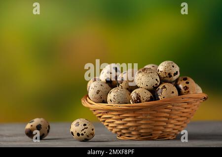 Œufs de caille frais dans un petit panier en osier sur un fond naturel Banque D'Images