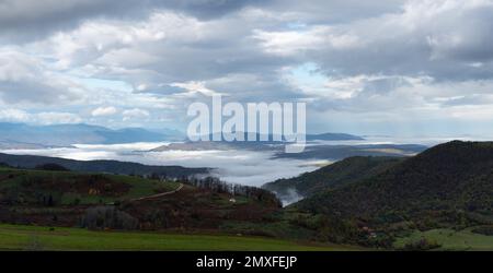 Paysage de montagne avec vallée remplie de brouillard et ciel nuageux le matin, saison d'automne dans les montagnes Banque D'Images