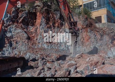 Travaux de machinerie lourde sur le chantier. Défrichement du sol rocheux pour la construction en Turquie. L'excavatrice écrase la roche. Banque D'Images