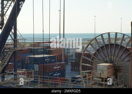 Vue sur la roue avec le câble de la grue du statif dans le terminal de conteneur avec les conteneurs rangés de différents expéditeurs à Livourne. Banque D'Images