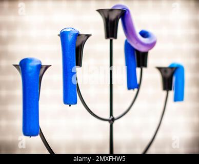 Bougies bleues et violettes sur un candélabre courbé par la chaleur, leurs mèches pointant vers le bas, à Bottrop, en Allemagne. Banque D'Images