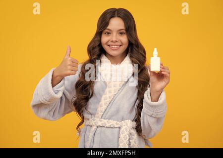 Une adolescente tient le médicament spray nasal du nez courant, une pandémie de virus. Jeune fille malade avec vaporisateur nasal sur fond jaune. Banque D'Images