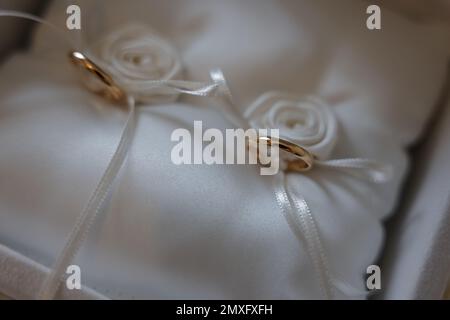 Un gros plan de bagues dorées de la livre de mariée dans un coussin spécial pour les anneaux Banque D'Images
