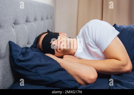 Vue de dessus d'un jeune homme portant un masque de sommeil reposant dans sa chambre. Détente, repos après le travail Banque D'Images