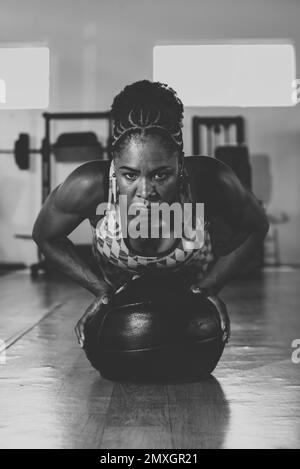 Déterminé femme faisant le soutien avec un ballon à la salle de gym. Renforcement de la colonne vertébrale et des bras. Banque D'Images