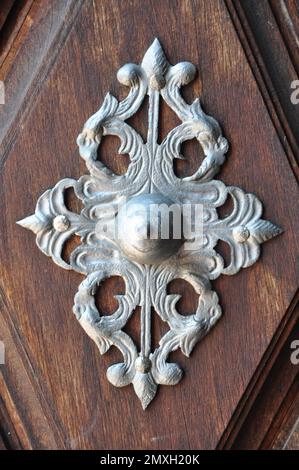 Ancienne porte en bois avec décor en métal sur des cubes en bois. Détail d'une porte en bois brun avec des motifs argentés faits avec beaucoup d'art .surligner pour le bouton Banque D'Images