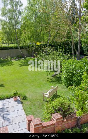 Banc de jardin en bois sur la pelouse dans un grand jardin de luxe britannique au printemps Banque D'Images