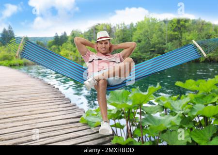 Homme reposant dans un hamac près de la rivière par beau temps Banque D'Images