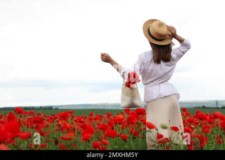 Femme avec sac à main et fleurs de pavot dans un beau champ Banque D'Images