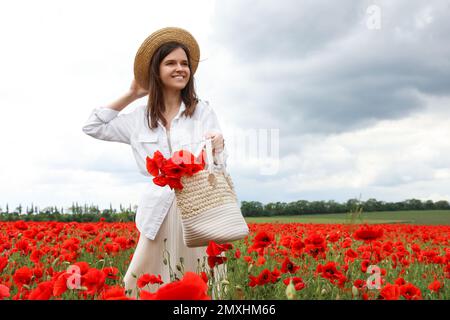 Femme tenant un sac à main avec des fleurs de pavot dans un beau champ Banque D'Images