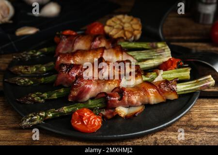 Asperges cuites au four, enveloppées de bacon sur une table en bois Banque D'Images