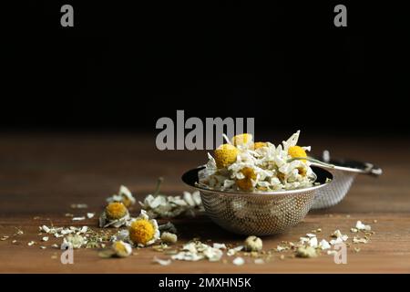 Sécher les fleurs de camomille dans l'infuser sur une table en bois, en gros plan Banque D'Images