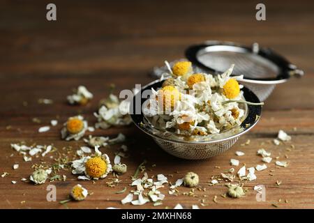 Sécher les fleurs de camomille dans l'infuser sur une table en bois, en gros plan Banque D'Images
