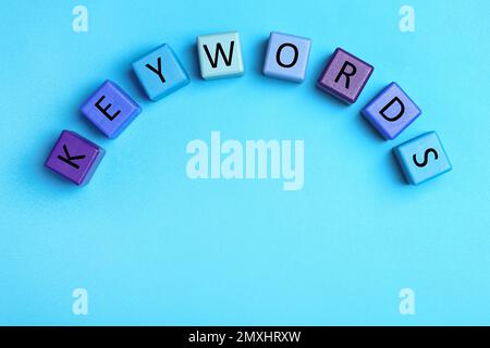 Cubes colorés avec mots-CLÉS sur fond bleu clair, plat. Espace pour le texte Banque D'Images