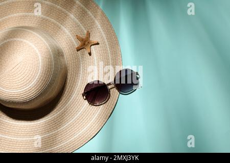 Chapeau élégant, étoile de mer et lunettes de soleil sur fond bleu clair, plat avec espace pour le texte. objets de plage Banque D'Images