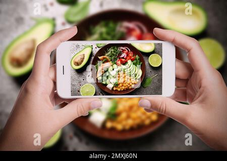 Blogueur prenant la photo de la salade délicieuse aux pois chiches à table, gros plan. Photographie alimentaire Banque D'Images