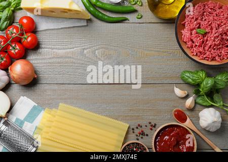 Cadre fait de lasagnes fraîches sur une table en bois gris, plat. Espace pour le texte Banque D'Images