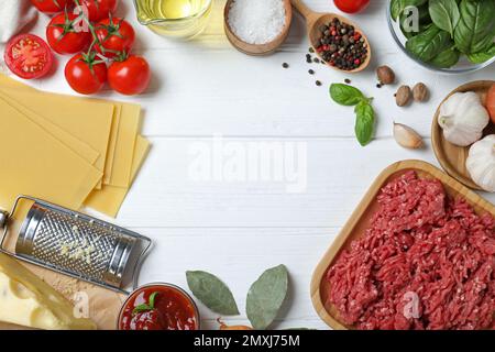 Cadre fait de lasagnes fraîches sur une table en bois blanc, plat. Espace pour le texte Banque D'Images