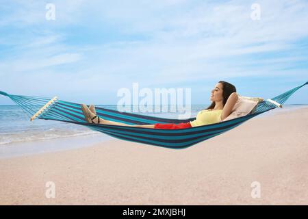 Femme se reposant dans un hamac près de la mer le jour ensoleillé Banque D'Images