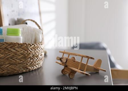 Panier en osier avec accessoires et avion en bois sur table grise dans la chambre pour enfants Banque D'Images