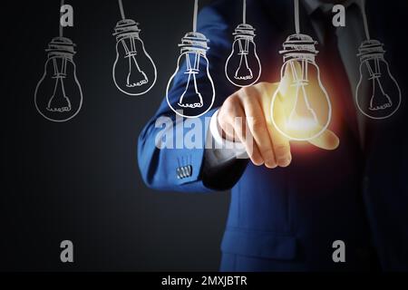 Concept d'idée. Homme d'affaires touchant l'ampoule lumineuse sur l'écran virtuel, gros plan Banque D'Images