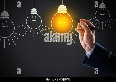 Concept d'idée. Homme d'affaires tirant une ampoule lumineuse sur l'écran virtuel, gros plan Banque D'Images