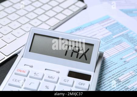 Calculatrice avec mot Tax, document et clavier sur table, gros plan Banque D'Images