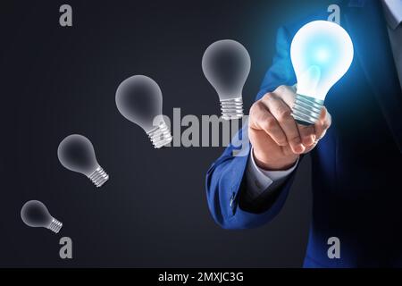 Concept d'idée. Homme d'affaires touchant l'ampoule lumineuse sur l'écran virtuel, gros plan Banque D'Images