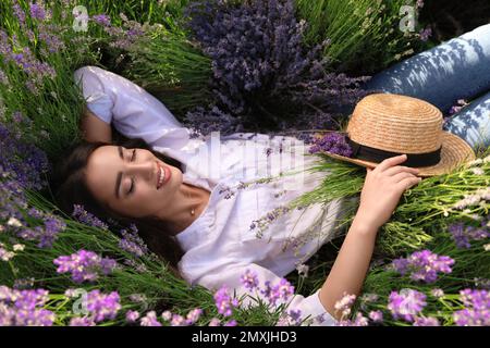 Jeune femme couché dans le champ de lavande le jour d'été Banque D'Images