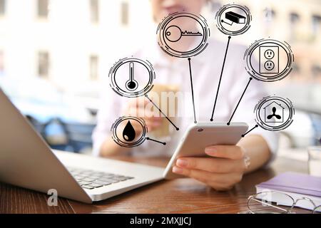 Femme utilisant l'application sur le téléphone mobile pour contrôler la maison intelligente, de gros plan. Systèmes automatiques Banque D'Images