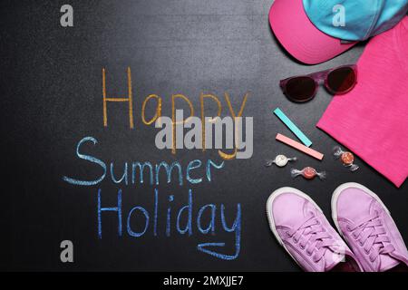 Composition Flat Lay avec chaussures pour enfant et inscription Happy Summer Holiday sur tableau noir. Pause-école Banque D'Images