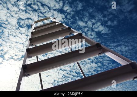 Escabeau en métal contre ciel bleu avec nuages, vue en angle bas Banque D'Images