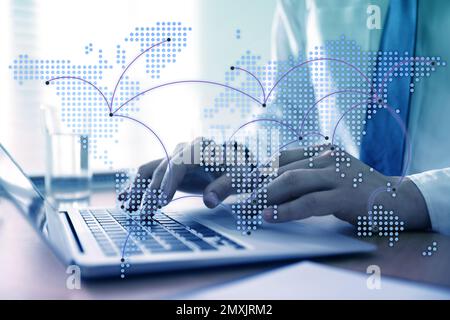 Concept de vente en gros et de logistique. Homme utilisant un ordinateur portable au bureau, illustration de la carte du monde au premier plan Banque D'Images