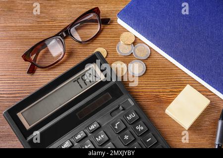 Calculatrice avec mot taxe, lunettes, pièces et carnet sur table Banque D'Images