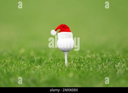 Balle de golf avec petit chapeau de père Noël sur le tee au parcours Banque D'Images