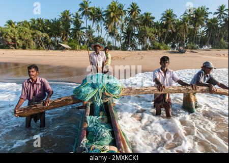 Pêcheurs au travail, pêcheurs poussant le bateau de pêche de la plage de sable dans la mer, pirogue à l'outrigger, Darwins Beach, Wella Odaya près de Ranna, S Banque D'Images