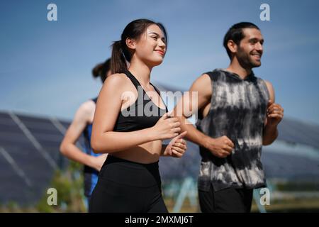 Active style de vie jeune homme coureur courir par panneaux solaires ferme à l'extérieur arrière-plan d'été. Concept de durabilité Banque D'Images